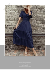 Dettaglio dell'abito blu scuro con scollo a V, bottoni decorativi e gonna a balze