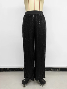 Detailed close-up of high-waist black sequin wide-leg trousers with elastic waistband