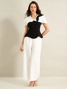 Détail d'un ensemble bicolore avec chemisier à cape, nœud noir et pantalon large blanc