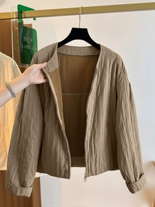 Detailed view of vertically quilted khaki zip-up jacket with textured fabric and round neck