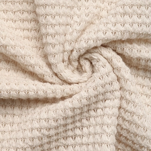 Détail macro du tissu gaufré crème montrant la texture tissée douce en relief 3D