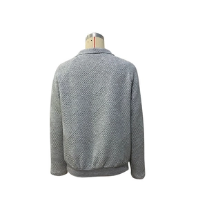 Detailopname van grijze sweater met geometrische textuur en geribbelde manchetten