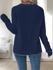 Detail of navy knit sweater featuring contrast white hand-stitch embroidery on hemline