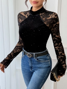Detail of elegant black velvet bodysuit with floral lace sleeves and sequin accents