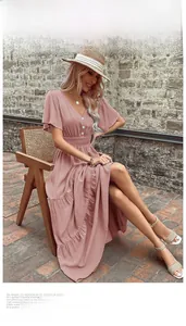 Dettaglio dell'abito rosa con scollo a V, bottoni, orlo a balze e vita a pieghe