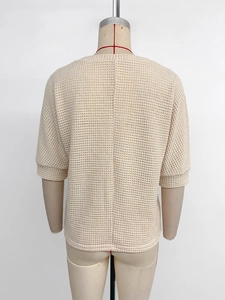 Détail de la couture dorsale verticale sur un haut crème en maille gaufrée