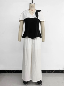 Détail d'un haut élégant noir et blanc à col en V avec nœuds et pantalon large blanc