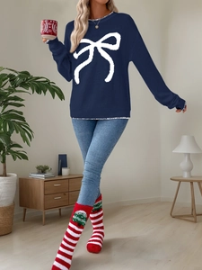 Close-up of navy knit sweater featuring a white bow pattern and striped Christmas socks