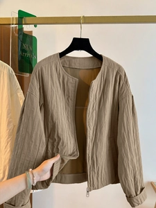 Detailed macro view of textured vertical quilting and zipper on a khaki cardigan jacket