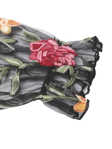 Detail of sheer black mesh sleeve with red rose embroidery and ruffled cuff design