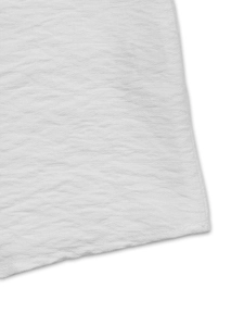 Macro view of white summer shirt featuring detailed waffle textured fabric and soft wave pattern