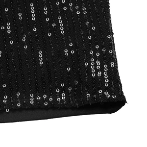 Detail view of shimmering black and silver sequins on high waist mesh trousers