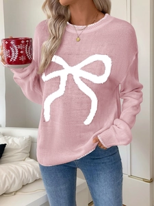 Detail of pink knitted sweater featuring white bow jacquard and crew neck design