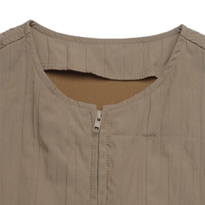 Close-up detail of casual khaki jacket featuring vertical plissé texture and metallic zipper
