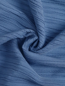 Detail of blue textured summer dress fabric showing soft seersucker weave and wavy patterns