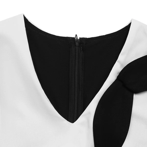 Détail de l'encolure en V élégante avec liseré noir et un grand nœud décoratif