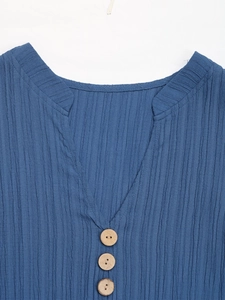 Close-up of V-neckline with wooden buttons and textured vertical pleated fabric in navy blue