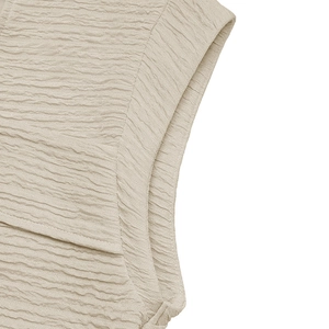 Macro detail of beige textured fabric with ruched pleated design on sleeveless top