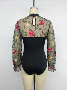 Detail of floral embroidery on sheer mesh back with double button closure at neck