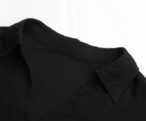 Detailed close-up of a black lapel collar with fine twill texture and uniform stitching