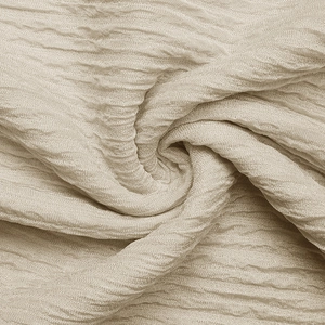 Close-up of beige textured fabric showing detailed pleated patterns and silky finish
