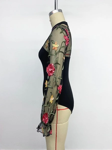 Detail view of floral embroidery on sheer mesh long sleeves of a black bodysuit