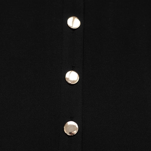 Detail of elegant black dress showing golden mirror buttons on the button-down placket