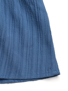 Detail view showing textured vertical pleats on deep blue summer dress fabric with hem stitching