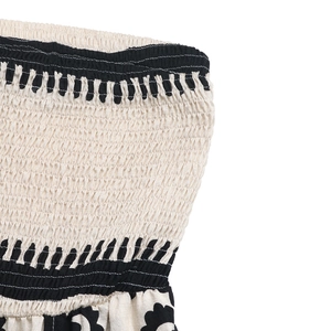 Detailed close-up of smocked bodice with bohemian embroidery on black and white strapless jumpsuit