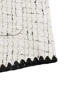 Detailed macro view of white tweed fabric texture with black crochet edge on a jacket