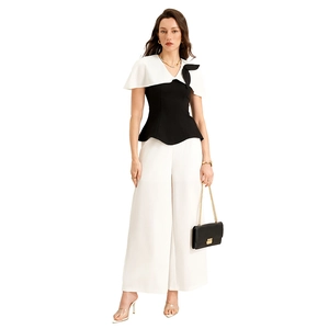 Ensemble élégant avec haut à basque noir, revers blanc et pantalon large taille haute