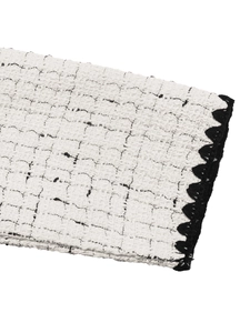 Detailed close-up of premium white tweed fabric texture with elegant black crochet trim