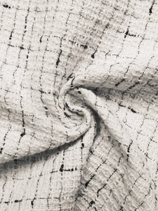 Close-up of white tweed fabric with black checks and subtle silver metallic threads