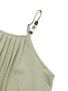 Detail of light green summer dress with pleated neckline and natural beaded straps