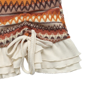 Close-up of bohemian knit dress with colorful wave patterns and white ruffled hem