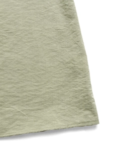 Close-up of sage green linen fabric showing natural texture and hem stitching on summer dress