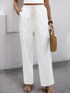 Detail of high-waist white linen trousers showing drawstring waist and front patch pockets
