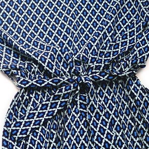 Detail of waist tie-up design and geometric print on a blue sleeveless dress