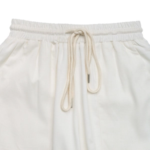 Detail of white high-waist linen trousers with elastic waistband and metal tip drawstring