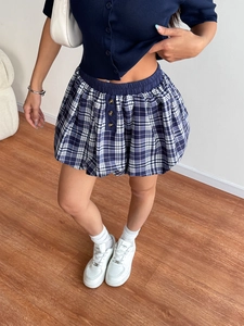 Detailed view of blue plaid puff skirt with elastic waist and brown decorative buttons