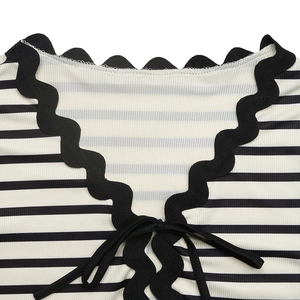 Detail of striped V-neck top featuring scalloped lace trim and ribbon bow tie design