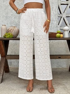 Detailed close-up of white crochet lace high waist trousers with tassel drawstring ties