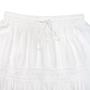 Détail de la jupe blanche en dentelle avec taille élastique, cordon et broderie ajourée