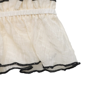 Détail du tissu gaufré blanc cassé avec bords contrastés noirs et smocks élastiques