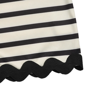 Detailed close-up of black and white striped knit fabric with scallop wave edge trim