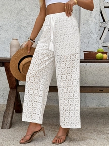 Detailed close-up of white lace wide-leg trousers featuring floral hollow-out patterns