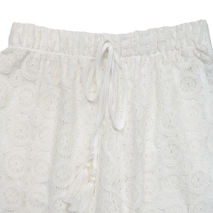Detail of high waist white lace pants with elastic drawstring and fringe tassels