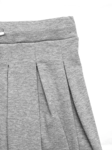 Détail de jupe plissée grise en tricot avec taille élastique et cordon de serrage blanc