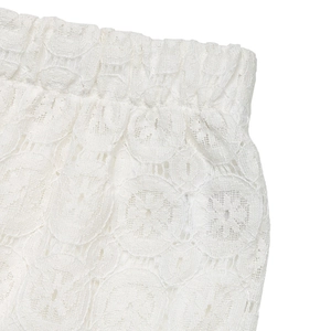 Detailed close-up of white floral lace fabric and elastic high waistband on trousers
