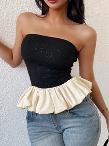 Detail of black glitter tube top with contrasting off-white ruffled peplum hem
